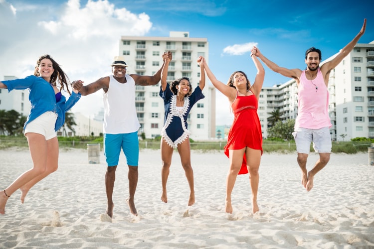 Five people jumping into the air smiling at the beach