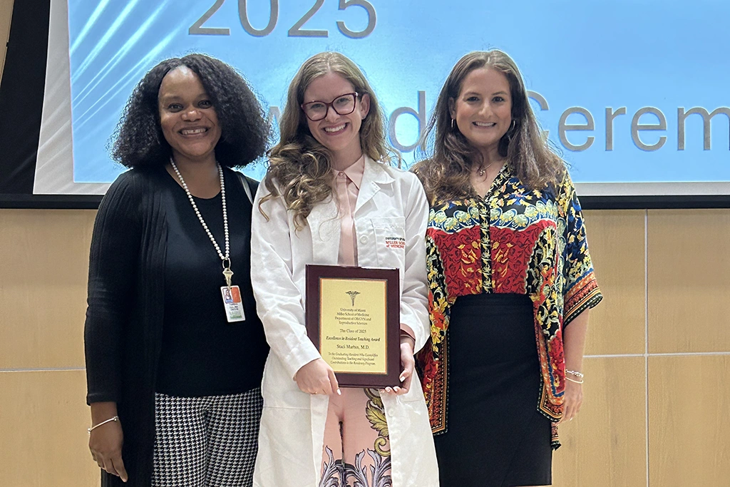 Three women pose with their award