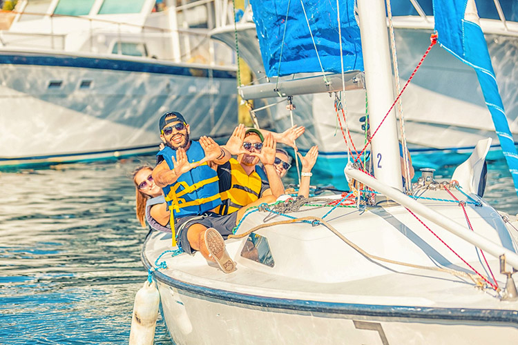 Adults in a sail boat holding up the U sign