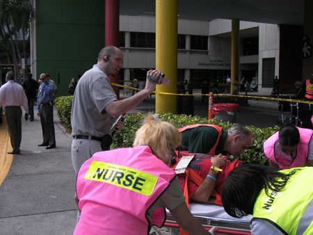 Nurses in pink vests work with a patient outside