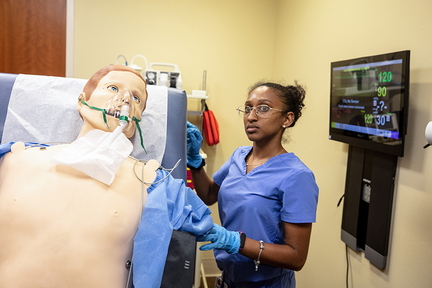Medical student engaging in a simulation with a dummy