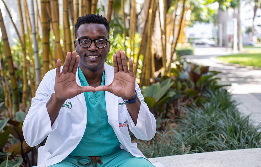 Student making the U with his hands on campus