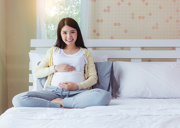 Pregnant woman sitting on a bed