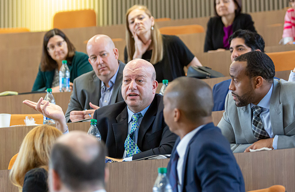 Man asking a question during a lecture with others seated around him