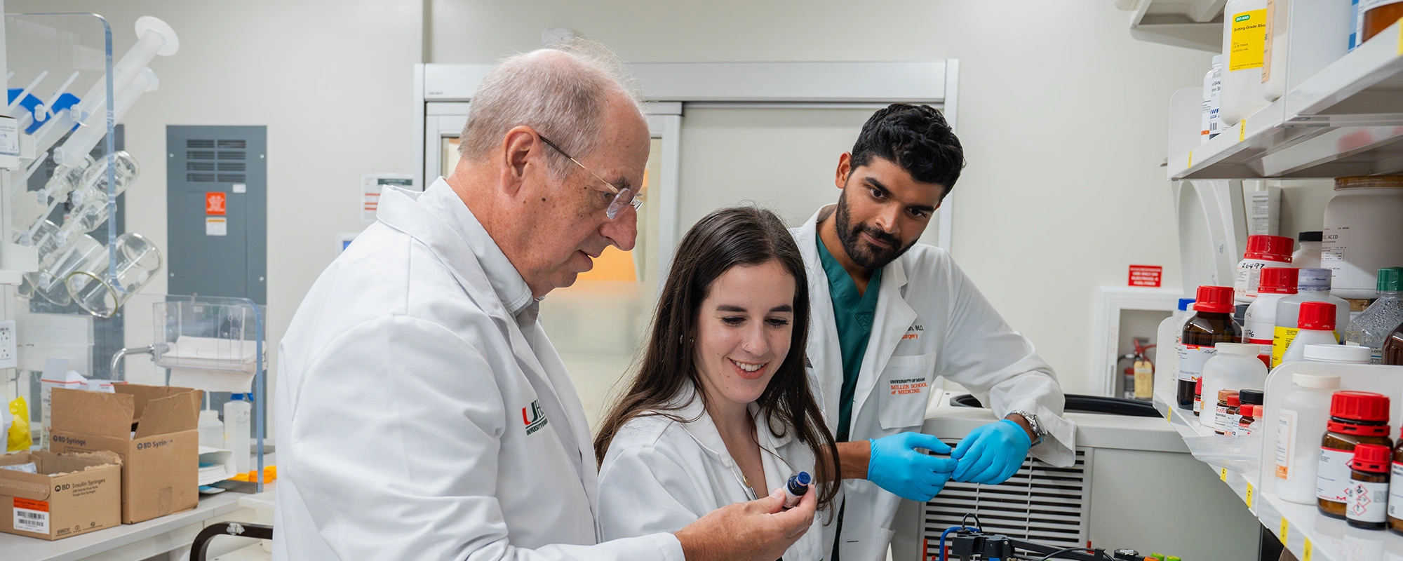 three researchers in labcoats working in a lab