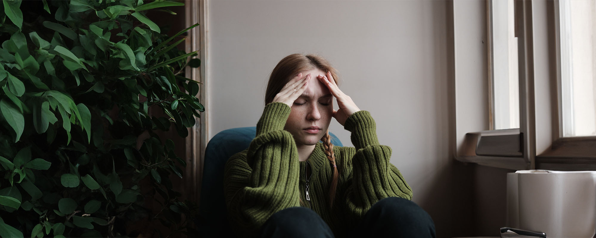 Young woman holding her head in pain in her living room