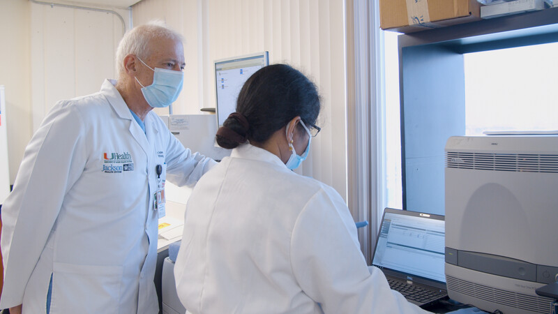 Dr. Andrews and another doctor, masked, at lab equipment
