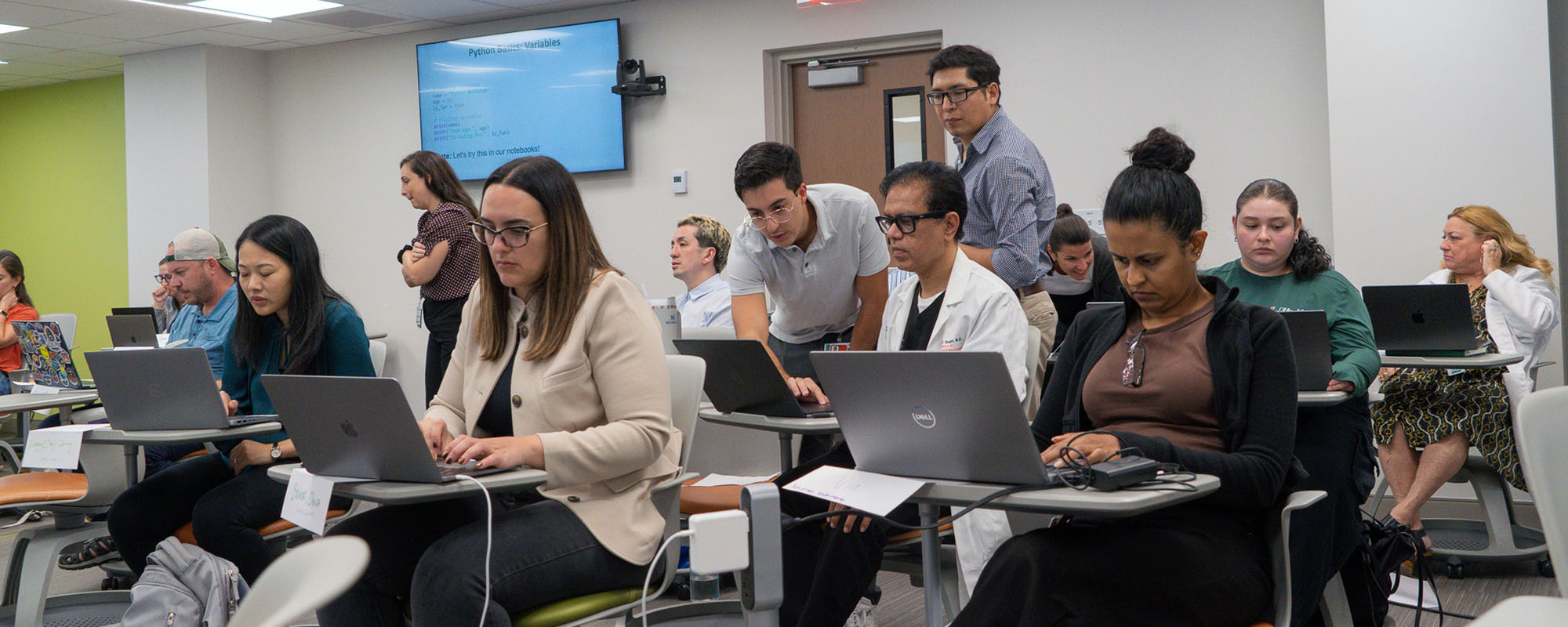 Participants in the Miller School of Medicine's AI workshop, sitting in a classroom and working on laptops
