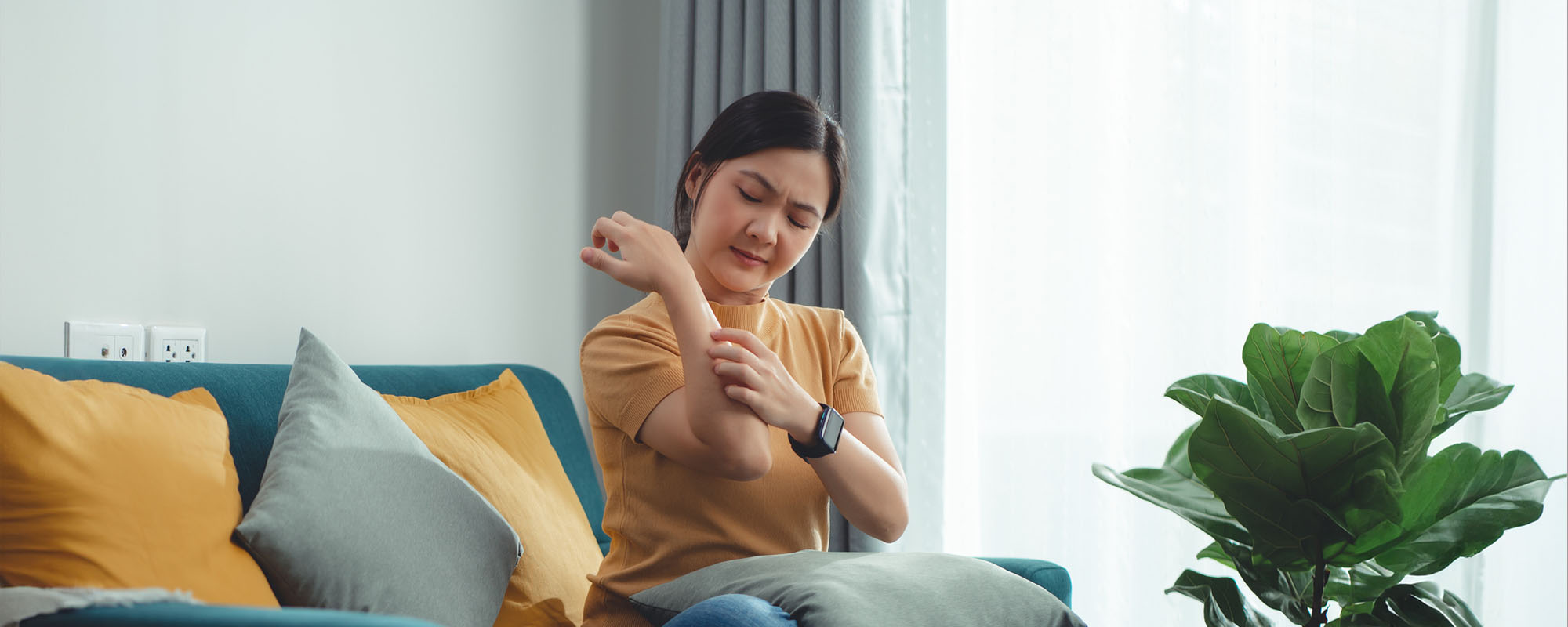 Woman sitting on a couch scratching her arm