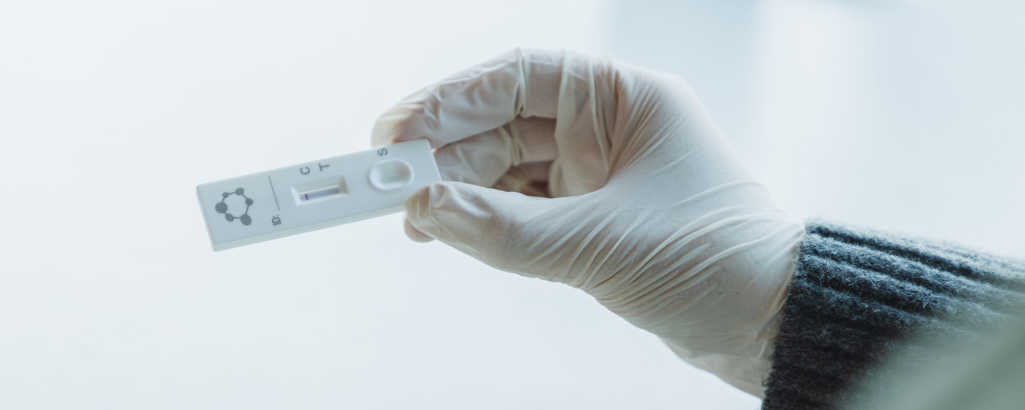 A negative COVID-19 test held by a gloved hand