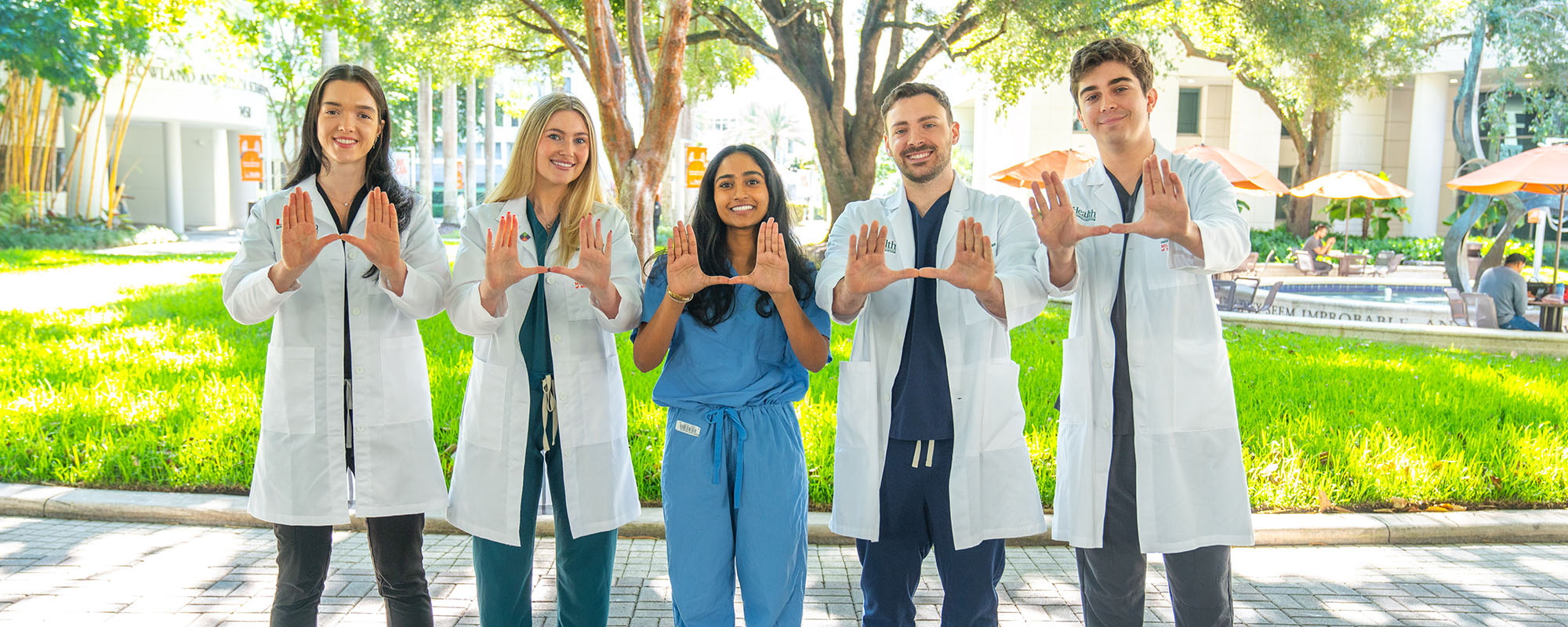 Four medical students who are part of the DREAM scholars program, flashing the U hand symbol