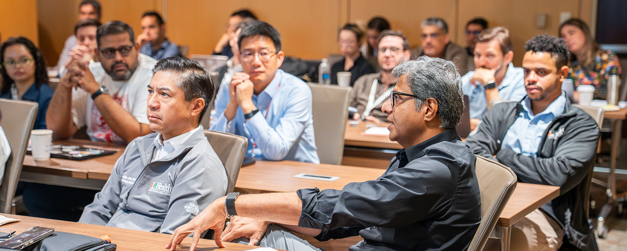 Attendees at the Desai Sethi Urology Institute research retreat, seated in a classroom, in conversation