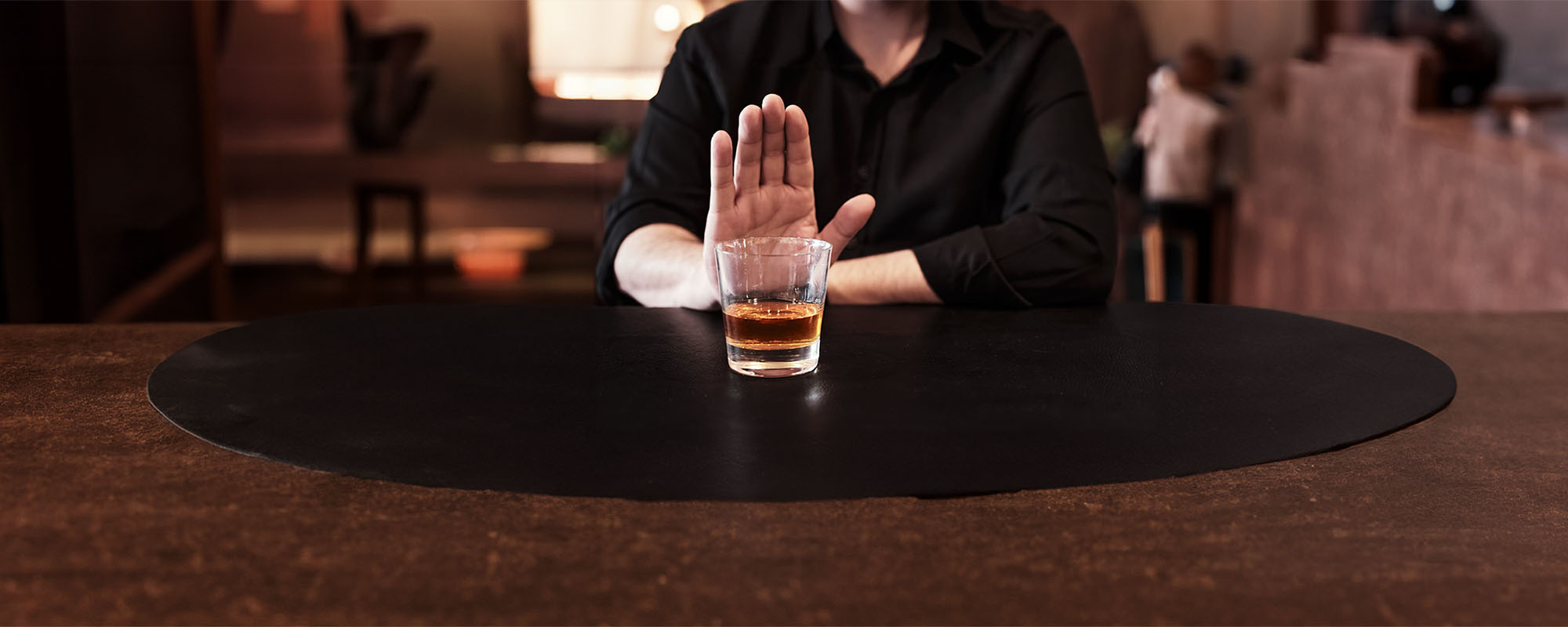 Man refusing a glass of dark alcohol