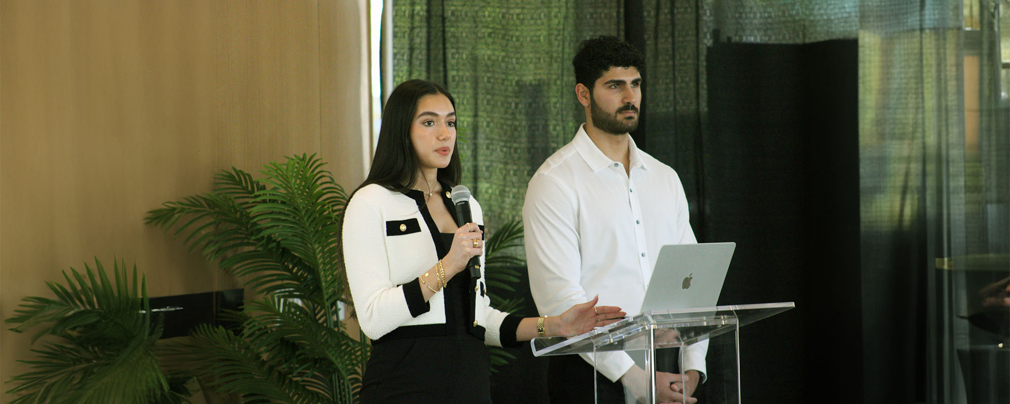 Medical students Yasmine Mohseni and Eric Sokhn speaking from a podium