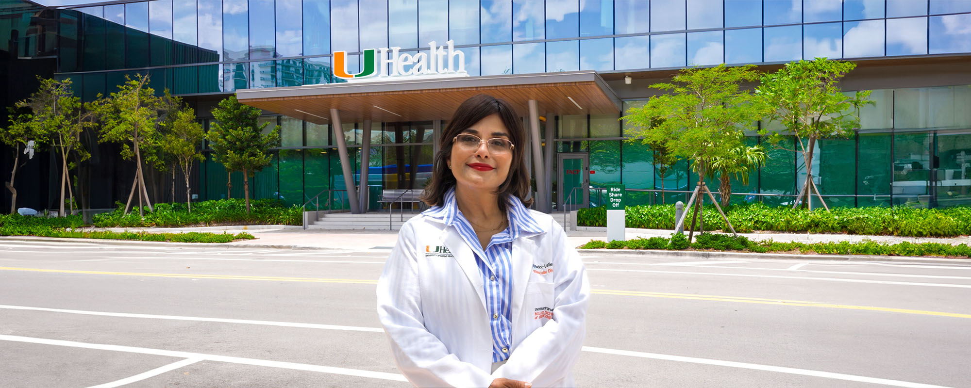 Dr. Maria Carolina Delgado-Lelievre in her white medical coat, standing in front of a UHealth building