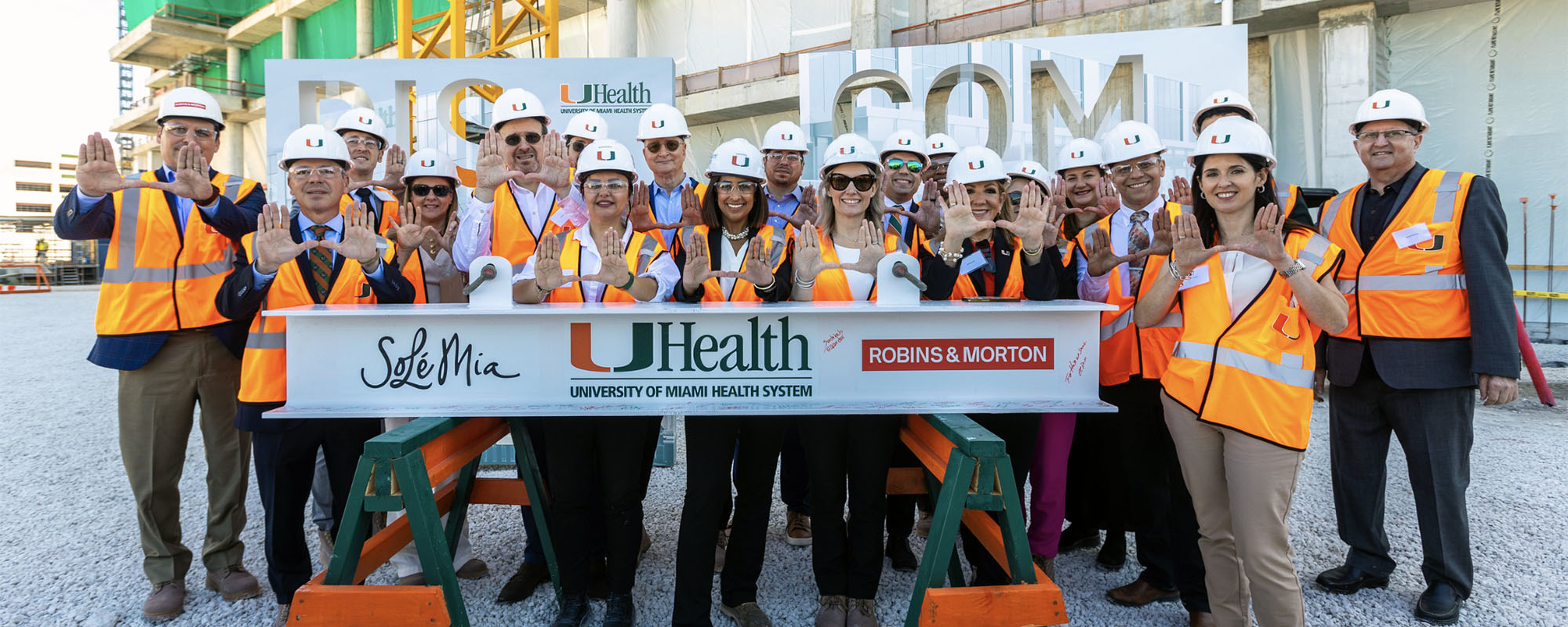 Attendees at the SoLé Mia topping off ceremony flash the U hand symbol